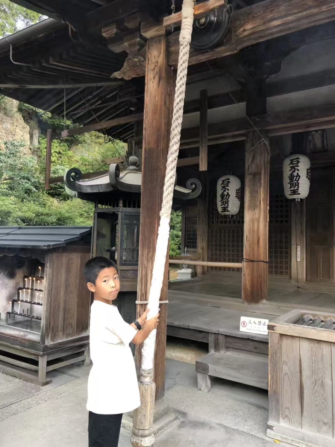 Pulling the bell rope at a wooden temple in Japan