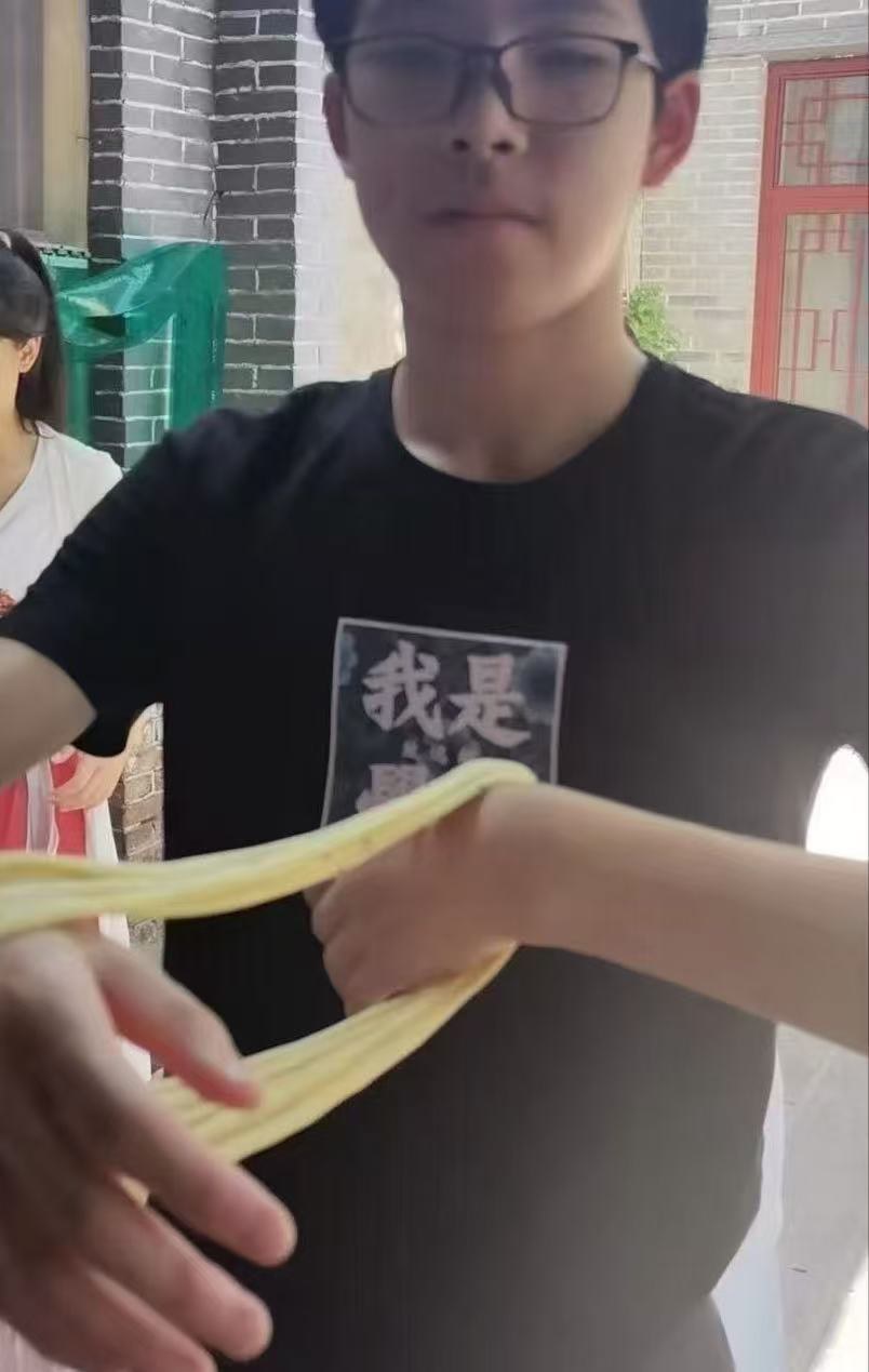 Hand-pulling sanzi, a fried twisted-dough snack, stretched into thin strands by hand