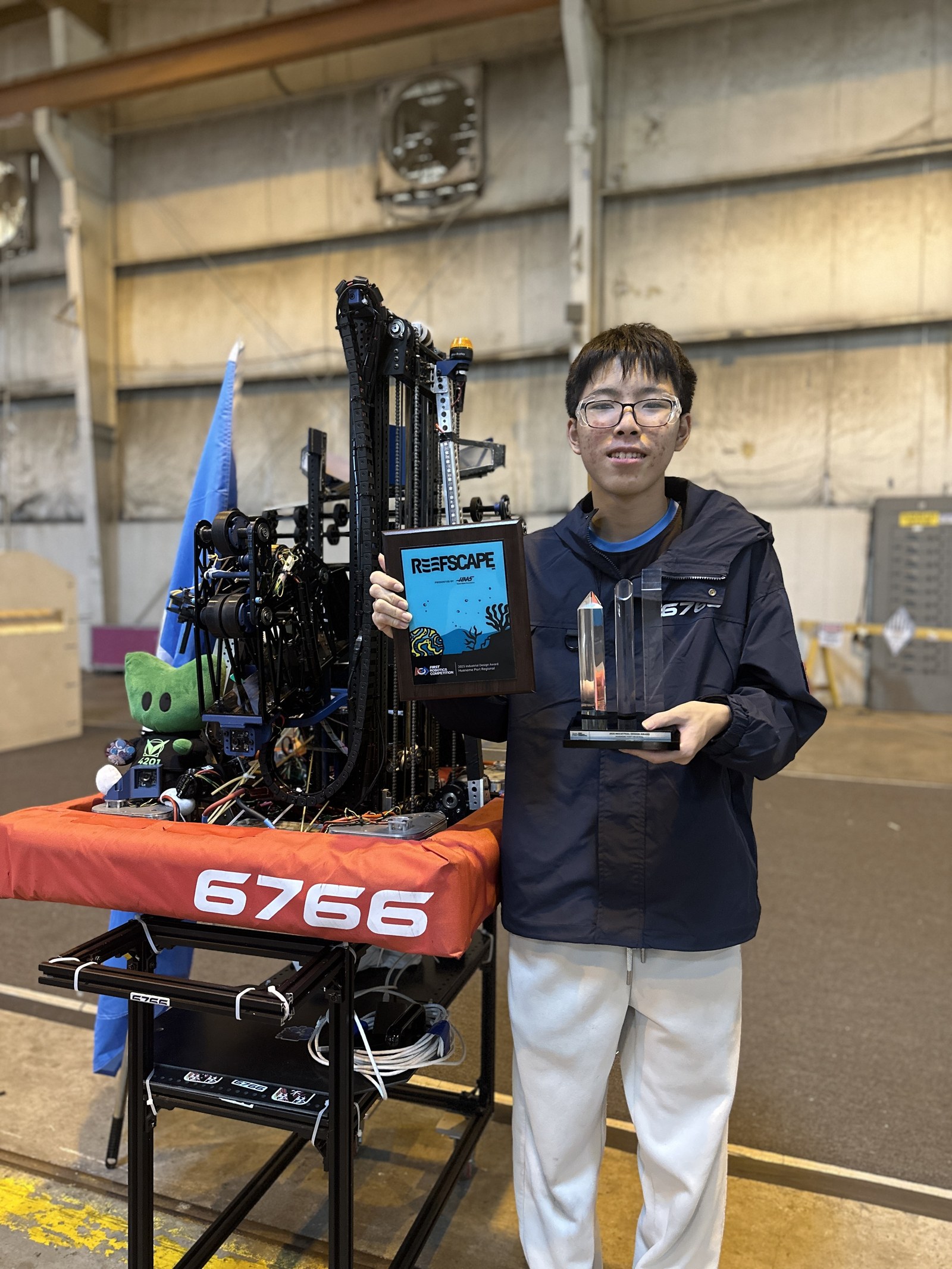 Holding the 2025 REEFSCAPE award medal and trophy beside robot 6766